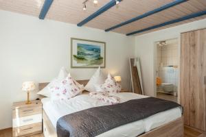 ein Schlafzimmer mit einem großen Bett mit rosa Kissen in der Unterkunft Hotel garni NordSeerose Greetsiel in Krummhörn
