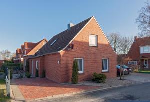 ein rotes Backsteinhaus mit einem schwarzen Dach in der Unterkunft Hotel garni NordSeerose Greetsiel in Krummhörn
