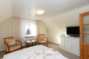ein Schlafzimmer mit einem Bett und einem Flachbildfernseher in der Unterkunft Hotel garni NordSeerose Greetsiel in Krummhörn