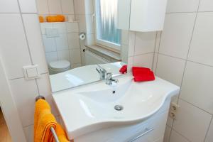 ein Badezimmer mit einem weißen Waschbecken und einem Spiegel in der Unterkunft Hotel garni NordSeerose Greetsiel in Krummhörn + 14 Fotos