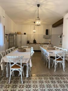 a dining room with white tables and chairs and a kitchen at Casa Elsa Almagro in Almagro
