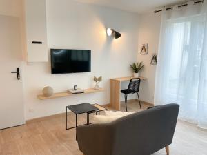 ein Wohnzimmer mit einem Sofa und einem Fernseher an der Wand in der Unterkunft COZYMAINE, superbe studio au coeur d'Angers in Angers