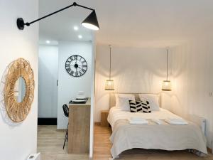 ein Schlafzimmer mit einem Bett und einer Uhr an der Wand in der Unterkunft COZYMAINE, superbe studio au coeur d'Angers in Angers