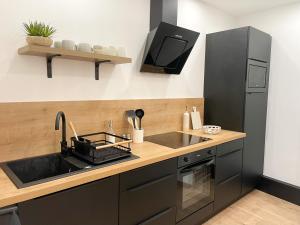 eine Küche mit einer Spüle und einem schwarzen Kühlschrank in der Unterkunft COZYMAINE, superbe studio au coeur d'Angers in Angers