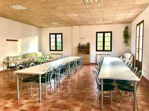 Habitación grande con mesas, sillas y ventanas. en Albergue de Castillazuelo en Castillazuelo