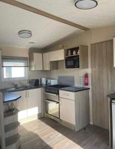 uma cozinha com armários brancos e um forno com placa de fogão em K & K Caravan Southview em Skegness