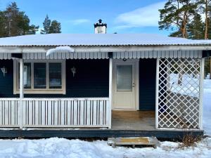 una casa azul con porche en la nieve en Fjällnära Stuga i Jämtland, en Svenstavik