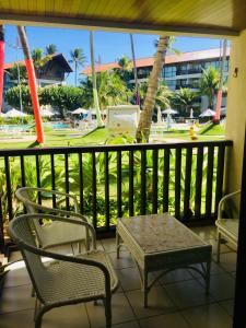 a balcony with chairs and a table and a view of a park at FLAT MARULHOS in Ipojuca