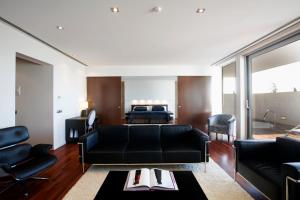 a living room with a black couch and a bed at Finca Prats Hotel Golf & Spa in Lleida