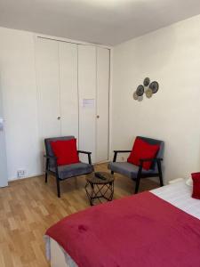 - une chambre avec deux chaises et un lit avec des oreillers rouges dans l'établissement APPART PORT DU CANAL, à Dijon
