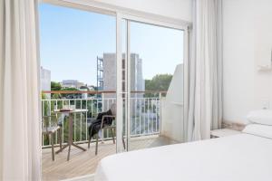 1 dormitorio con 1 cama y balcón con vistas. en Hotel Atolon, en Cala Bona