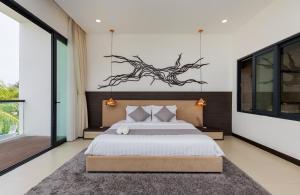 a bedroom with a bed with a branch on the wall at La Luxury Villas - Vung Tau in Vung Tau