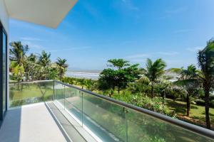 a balcony with a view of the ocean and palm trees at La Luxury Villas - Vung Tau in Vung Tau