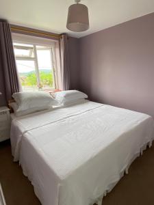 Un dormitorio con una gran cama blanca con ventana. en Pound Corner, en Godalming