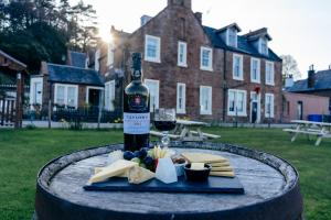 a bottle of wine and cheese on a table with a glass at The Corrie Hotel in Corrie