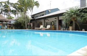 een groot blauw zwembad voor een gebouw bij Pousada Villa Caiobá in Matinhos
