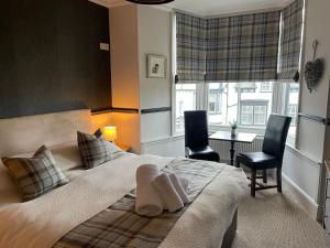 a bedroom with a bed with two chairs and a table at The Royal Oak Inn in Bowness-on-Windermere