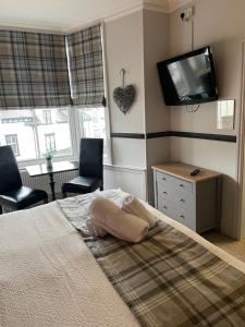 Schlafzimmer mit einem Bett, einem TV und 2 Stühlen in der Unterkunft The Royal Oak Inn in Bowness-on-Windermere