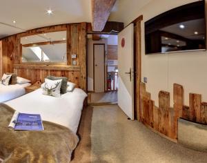 Duas camas num quarto com paredes de madeira em Hôtel Les Cimes em Megève