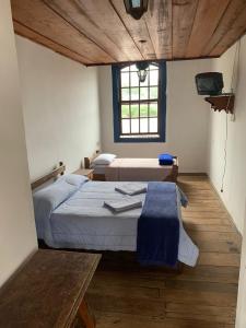 a bedroom with two beds and a table in it at Pousada Vila Rica in Ouro Preto