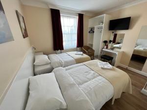 Cette chambre comprend deux lits et une télévision. dans l'établissement Melbourne House Hotel, à Londres
