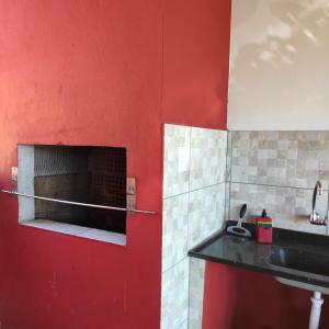 cocina con pared roja y chimenea en Casa Mágica, en Praia do Rosa