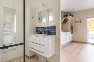 Un baño blanco con lavabo y espejo. en Manava, en Vaux-sur-Mer