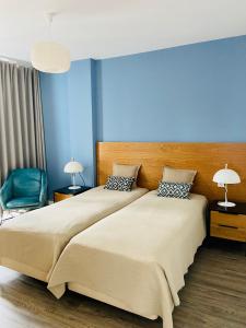 een slaapkamer met een groot bed en een blauwe muur bij Ocean Cliffs Apartments in Funchal