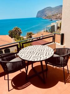 una mesa y sillas en un balcón con vistas al océano en Ocean Cliffs Apartments en Funchal