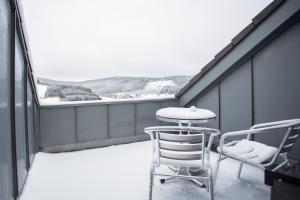 uma varanda coberta de neve com uma mesa e cadeiras em Am Kleehagen 51-F, Niedersfeld-Winterberg em Winterberg