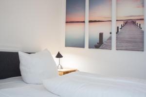 1 dormitorio con 1 cama blanca y 4 cuadros en la pared en Welcome in - Am Kleehagen 51-F, Niedersfeld-Winterberg, en Winterberg