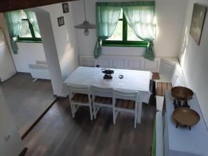 a white table and chairs in a room with two windows at Bakina iža in Duga Resa