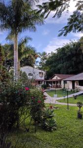 a garden with a palm tree and a house at Pousada Chez Nous in Penedo