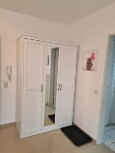 einen weißen Schrank in einem Zimmer mit Spiegel in der Unterkunft Airport Apartments Valentina in Meckenbeuren