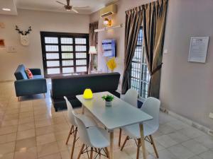 a dining room and living room with a table and chairs at Semi-Detached, Up to 24 Pax, 3200sqft, 4 Bedrooms, 3 Bathrooms, 4 Car Parks in Bayan Lepas