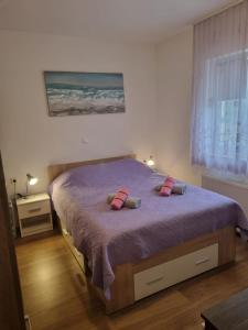 1 dormitorio con cama con sábanas moradas y almohadas rosas en Apartmani Marina & Ana, en Poreč