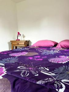 a purple bed with pink pillows and a purple blanket at Eden Cottage in Saint Gatien des Bois