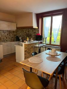 uma cozinha com uma mesa de madeira e cadeiras numa cozinha em Le moulin Bertrand em Martigny-Courpierre