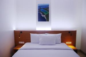 a bed in a hotel room with a picture on the wall at Grand Thamrin Hotel in Jakarta