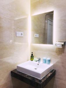 een badkamer met een witte wastafel en een spiegel bij Grand Thamrin Hotel in Jakarta