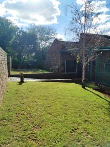 une cour avec un arbre et une maison en briques dans l'établissement Shandi Accommodation, à Witbank