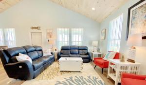 Una sala de estar con un sofá azul y sillas rojas. en At Long Last home, en Crystal Beach