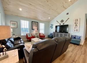sala de estar con muebles de cuero y TV de pantalla plana en At Long Last home, en Crystal Beach