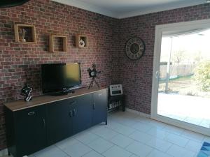 un soggiorno con TV e muro di mattoni di Gîte Au fil de l'eau a Muides-sur-Loire