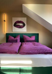 1 dormitorio con 1 cama con mantas y almohadas moradas en Five en Coblenza