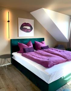 Un dormitorio con una cama grande con mantas y almohadas púrpuras. en Five, en Coblenza