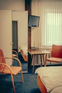 a room with chairs and a table and a bed at Inselgaestehaus-Erna in Putbus
