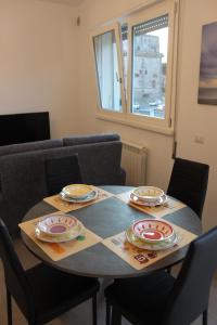 - une table à manger avec des chaises et des assiettes dans l'établissement Appartamento Torre Matilde, à Viareggio