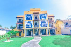 a yellow building with blue balconies and a yard at Amanda Beach Villas in Unawatuna