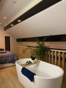 a large white bath tub in a room with a bed at COCOONING near DINANT 300m from River Meuse in Blaimont